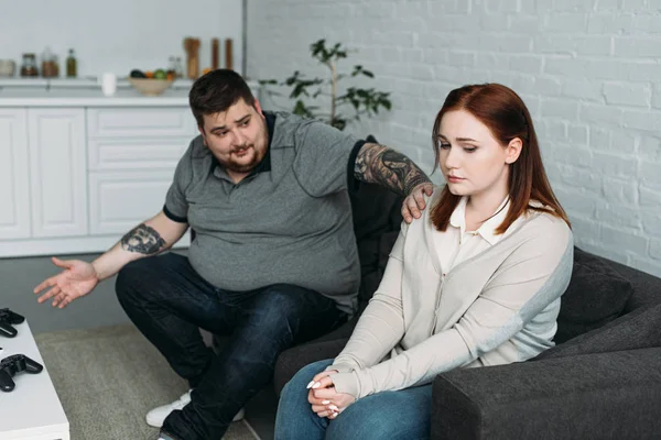 Boyfriend gesturing and touching sad girlfriend at home — Stock Photo
