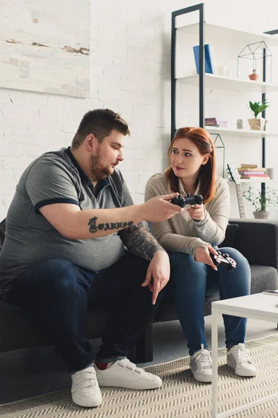 Girlfriend giving joystick to overweight boyfriend at home — Stock Photo