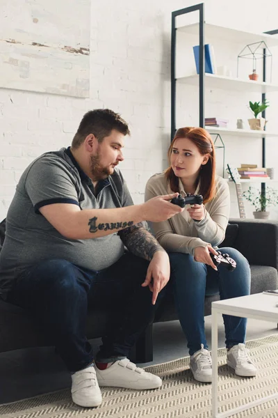 Namorada dando joystick para namorado com sobrepeso em casa — Fotografia de Stock