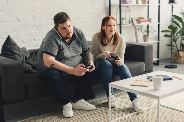 Couple playing video game and boyfriend talking by smartphone at home — Stock Photo