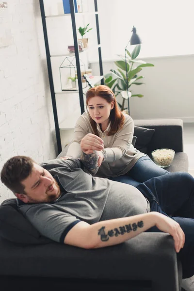 Freundin nimmt Freund die Hand und sitzt zu Hause auf Sofa — Stockfoto