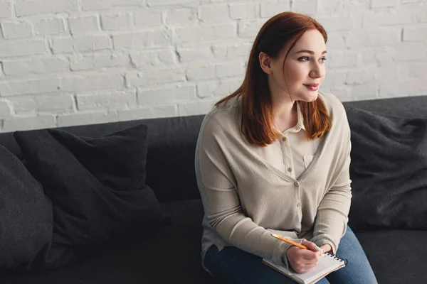 Bella ragazza in possesso di notebook e matita e guardando lontano a casa — Foto stock