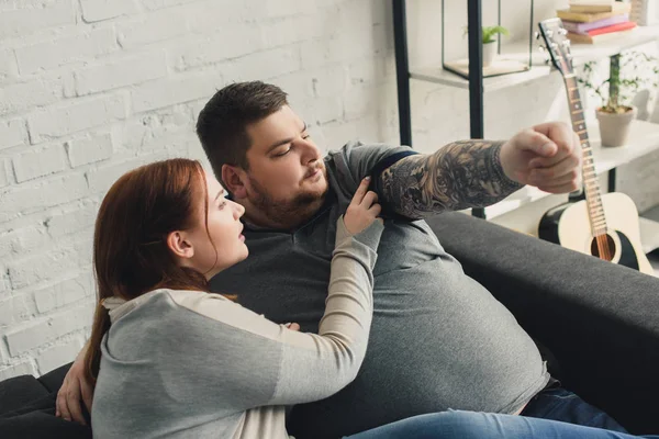 Girlfriend looking at boyfriend tattooed arm at home — Stock Photo