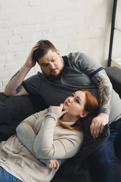 Pensive boyfriend and girlfriend lying on sofa at home — Stock Photo