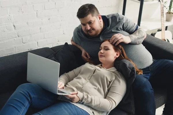 Boyfriend touching girlfriend hair and looking at laptop at home — Stock Photo