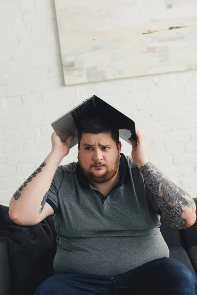 Красивий чоловік тримає ноутбук на голові і дивиться вдома — стокове фото