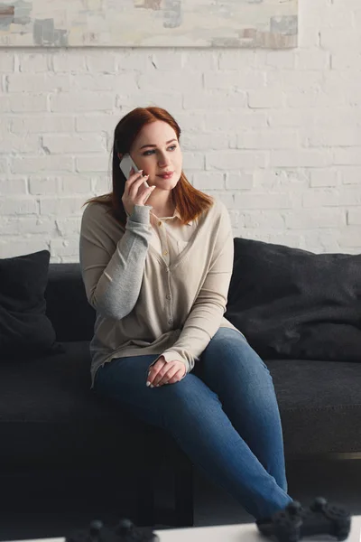 Красива дівчина розмовляє смартфоном на дивані вдома — стокове фото