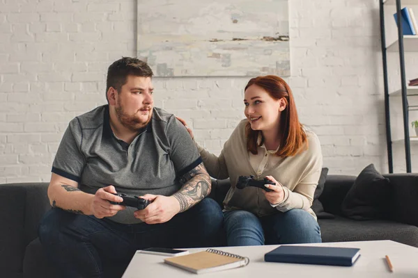 Sorrindo namorada palmando namorado enquanto joga videogame em casa — Fotografia de Stock