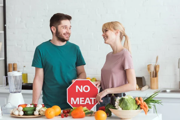 Couple of vegans looking at each other with no meat sign in kitchen — Stock Photo