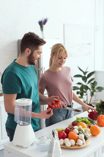 Sonriente pareja de veganos cocinar en la cocina - foto de stock