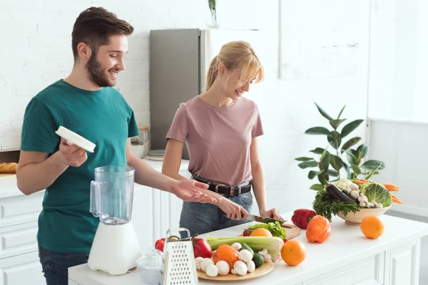 Pareja de veganos cocinar alimentos en la cocina - foto de stock