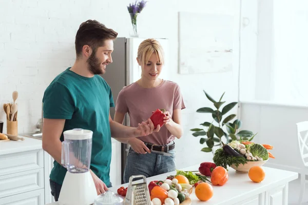 Couple of vegans looking at red bell pepper at kitchen — Stock Photo