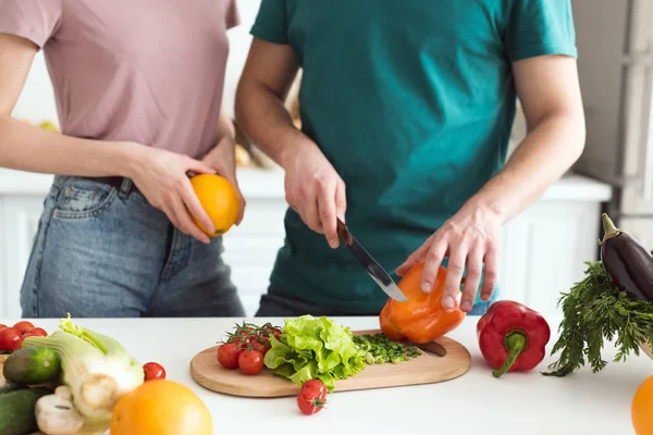 Imagen recortada de novio cortando verduras para ensalada vegetariana en la cocina - foto de stock