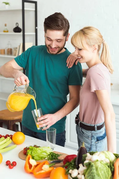 Glücklicher veganer Freund gießt in Küche frischen Saft ins Glas — Stockfoto