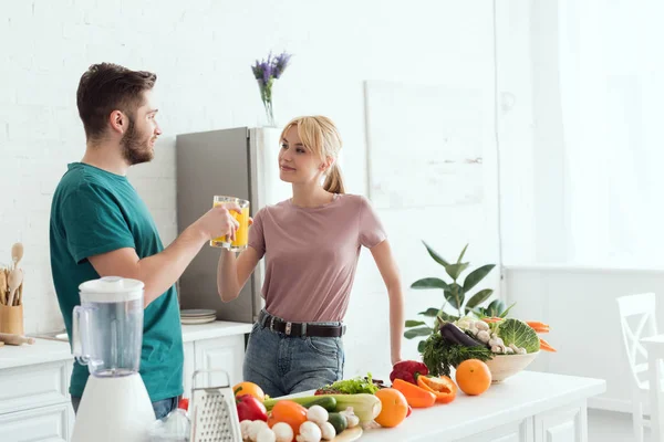 Ein paar Veganer klappern in der Küche mit Orangensaft — Stockfoto