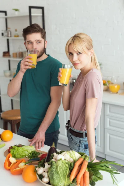 Pareja de veganos bebiendo jugo fresco en la cocina - foto de stock