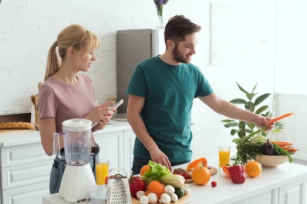 Pareja de veganos usando tableta con receta para preparar alimentos en la cocina - foto de stock