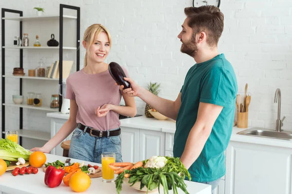 Хлопець використовує баклажани як мікрофон і розважається на кухні, веганська концепція — стокове фото