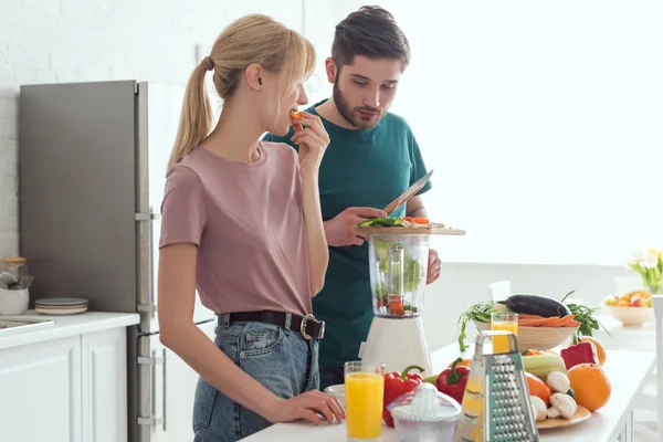 Namorado preparando suco de legumes com espremedor na cozinha, conceito vegan — Fotografia de Stock