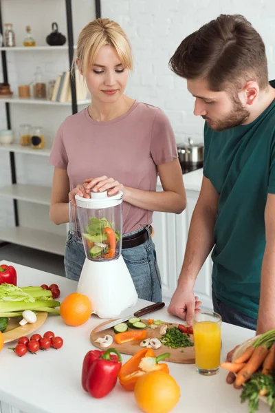 Couple de végétaliens préparant jus de légumes à la cuisine — Photo de stock