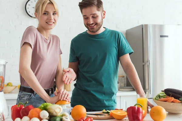 Couple of vegans preparing juice with squeezer at kitchen — Stock Photo