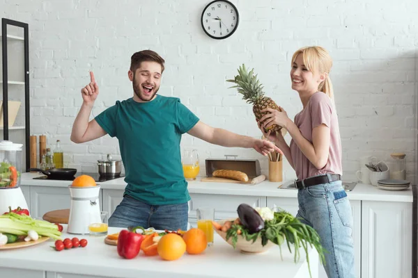 Улыбающаяся пара вегетарианцев веселятся во время приготовления пищи на кухне — стоковое фото