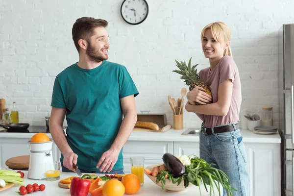 Young vegan couple with fresh fruits and vegetables in kitchen at home — Stock Photo