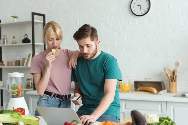 Porträt eines veganen Paares, das zu Hause in der Küche gemeinsam Laptop benutzt — Stockfoto