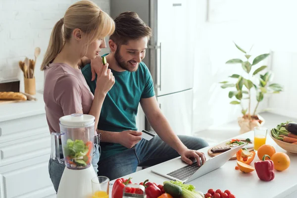 Vegan couple using laptop together in kitchen at home — Stock Photo