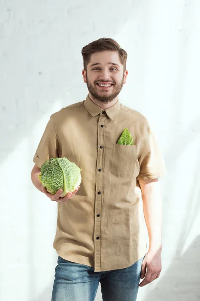 Ritratto di giovane uomo sorridente con verza fresca in mano, concetto di stile di vita vegano — Foto stock