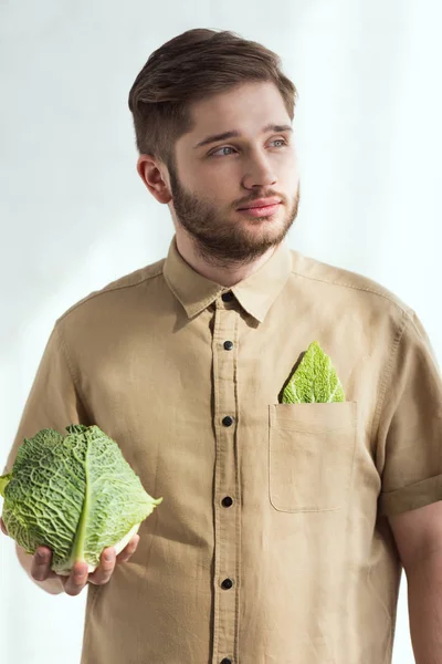 Ritratto di giovane pensoso con verza fresca in mano, concetto di stile di vita vegano — Foto stock