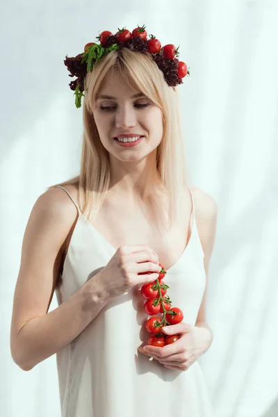 Mulher sorridente com tomates cereja em mãos e grinalda feita de alface fresca e tomates cereja, conceito de estilo de vida vegan — Fotografia de Stock