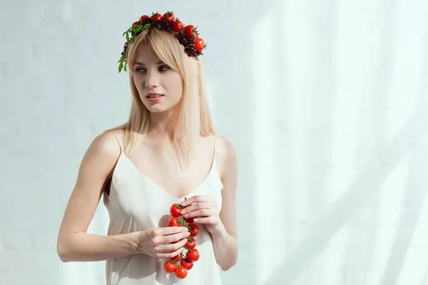 Woman with cherry tomatoes in hands and wreath made of fresh lettuce and cherry tomatoes, vegan lifestyle concept — Stock Photo