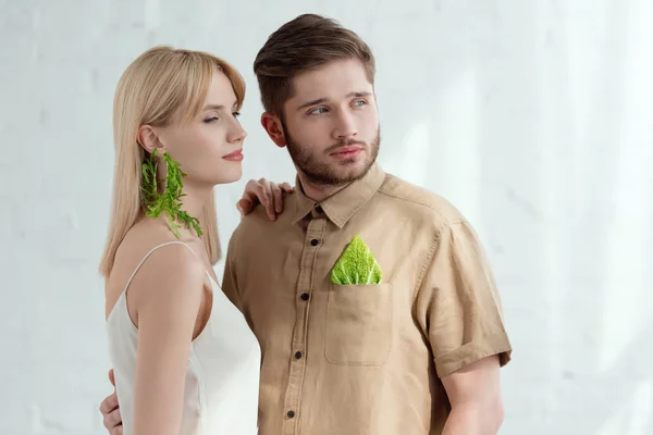 Woman with earring made of arugula and boyfriend with savoy cabbage leaf in pocket, vegan lifestyle concept — Stock Photo