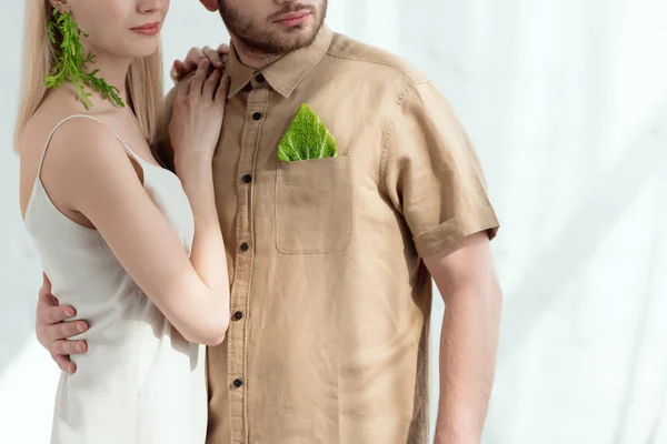 Cropped shot of woman with earring made of arugula lean on boyfriend with savoy cabbage leaf in pocket, vegan lifestyle concept — Stock Photo