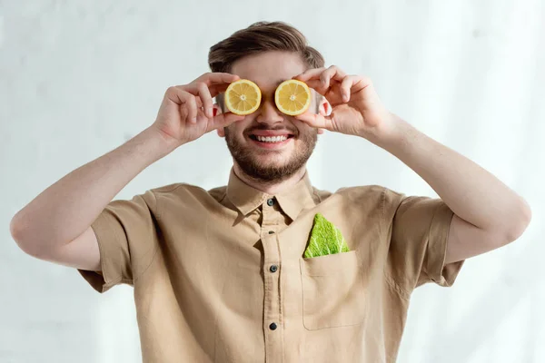 Vista oscurecida del hombre sonriente con trozos de limón y hoja de col savoy en el bolsillo, concepto de estilo de vida vegano - foto de stock