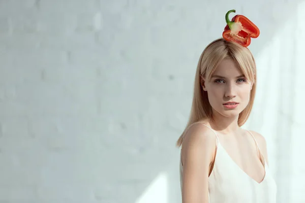 Junge hübsche Frau mit rotem Paprika auf dem Kopf, veganes Lifestylekonzept — Stockfoto