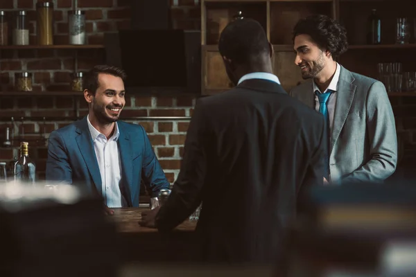 Selective focus of smiling young male friends in suits having party together — Stock Photo