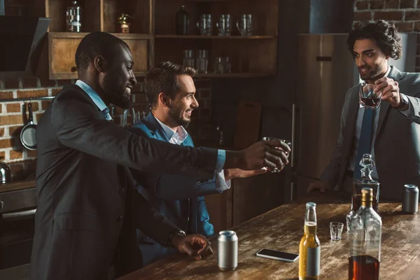 Heureux hommes multiethniques boire du whisky et faire la fête ensemble — Photo de stock