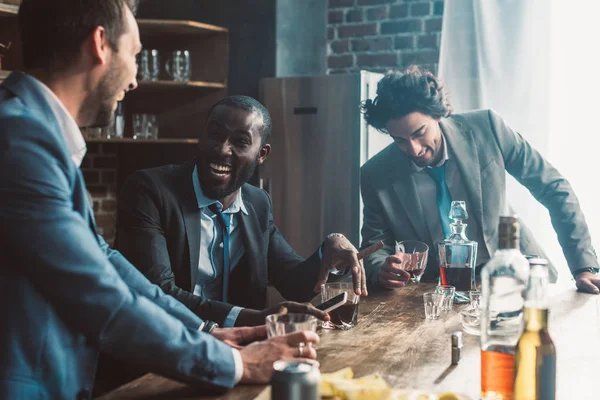 Alegre macho amigos riendo y bebiendo whisky juntos - foto de stock