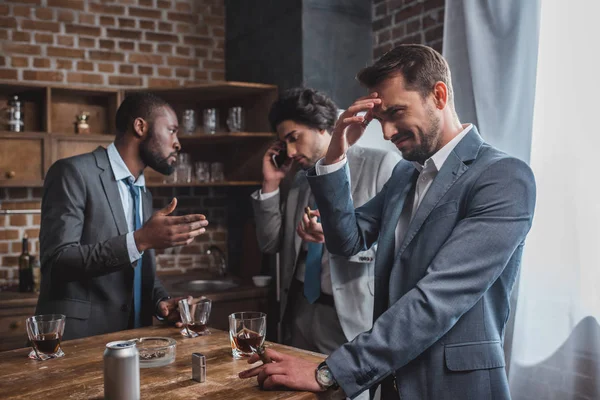 Hombres borrachos multiétnicos en trajes fumando cigarros y amigos hablando por teléfono inteligente - foto de stock