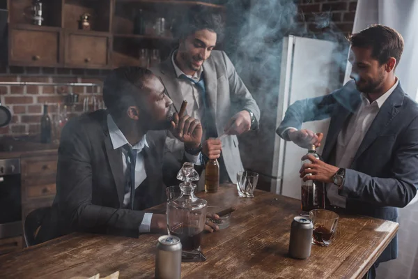 Junge multiethnische Geschäftsleute rauchen Zigarren und trinken alkoholische Getränke — Stockfoto