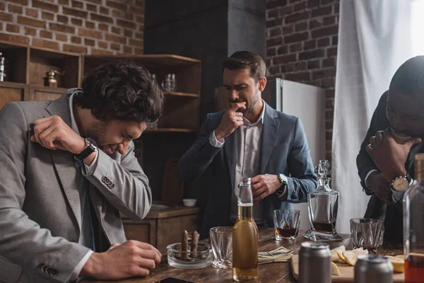 Multiethnic businessmen eating lemon slices and drinking tequila together — Stock Photo