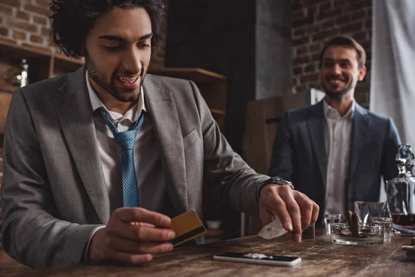 Primer plano vista de sonriente hombre en traje tomando drogas mientras amigo de pie detrás - foto de stock