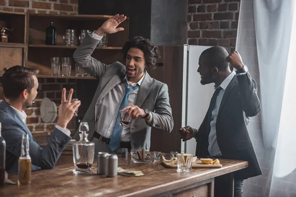 Alegres empresarios multiétnicos bebiendo whisky y festejando juntos — Stock Photo