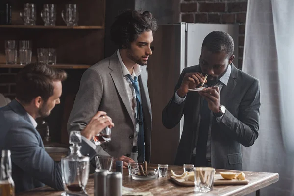 Empresarios multiétnicos que beben whisky y consumen drogas en el interior - foto de stock