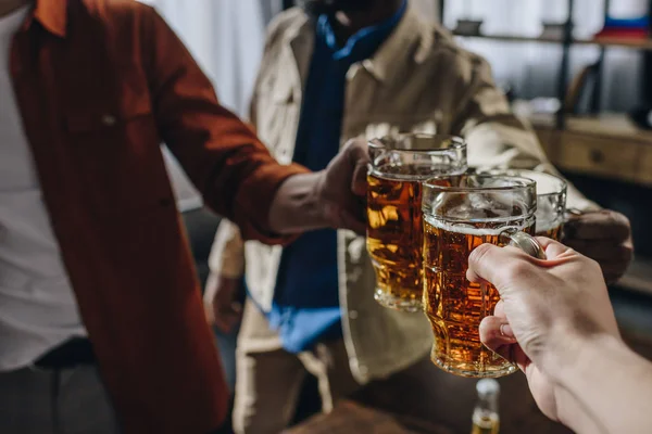 Обрезанный снимок друзей-мужчин, звонящих в бокалы пива — стоковое фото