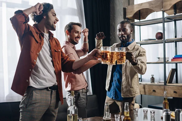 Aufgeregte männliche Freunde klirren beim gemeinsamen Feiern mit Biergläsern — Stockfoto