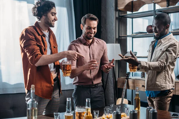 Souriants jeunes hommes multiethniques parlant et buvant des boissons alcoolisées ensemble — Photo de stock