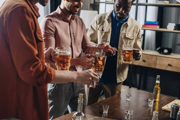 Plan recadré d'hommes souriants et multiethniques buvant ensemble des boissons alcoolisées — Photo de stock